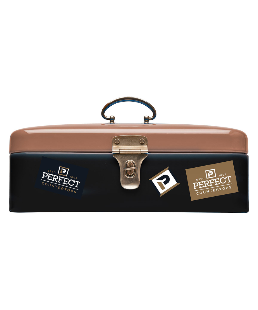 Metal toolbox with a brown lid and black base featuring three “Perfect Countertops” logo stickers. The stickers vary in color—navy blue, gold, and white—and display a bold “P” icon along with the company name and “ESTD 2003,” adding a branded, professional touch to the tool carrier.